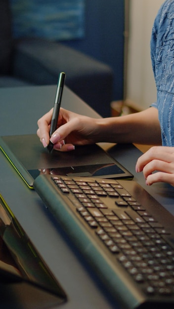 Gros plan sur l'équipement de retouche photo au studio de photographie sur le bureau. Femme travaillant comme éditrice à l'aide d'un logiciel de retouche, d'un clavier et d'une tablette graphique avec stylet pour un projet multimédia de retouche