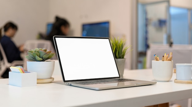 Gros plan sur un espace de travail portable avec papeterie pour ordinateur portable et pot de fleurs dans la salle de bureau