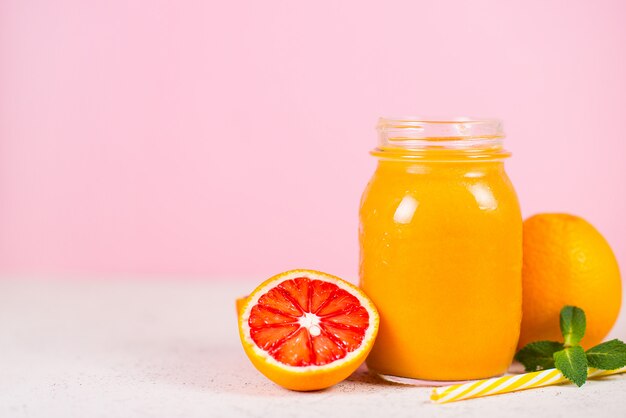 Gros plan est un pot de smoothie jaune frais à base de fruits naturels sur fond rose.