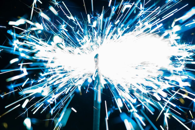 Gros plan des étincelles bleues d'un feu brûlant sur fond noir en l'honneur de la fête.