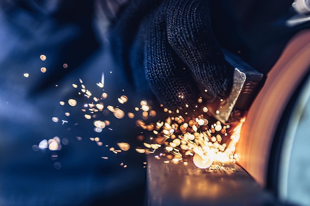 Gros plan d'étincelles qui s'envolent lors du meulage des détails métalliques de l'usine métallurgique de la machine