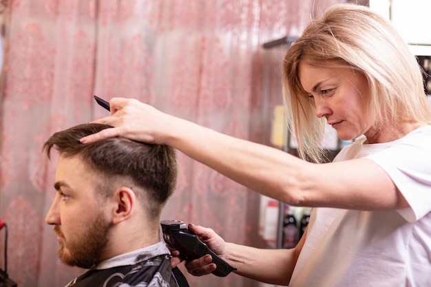 Gros plan d'un étudiant de sexe masculin ayant une coupe de cheveux avec une tondeuse à cheveux