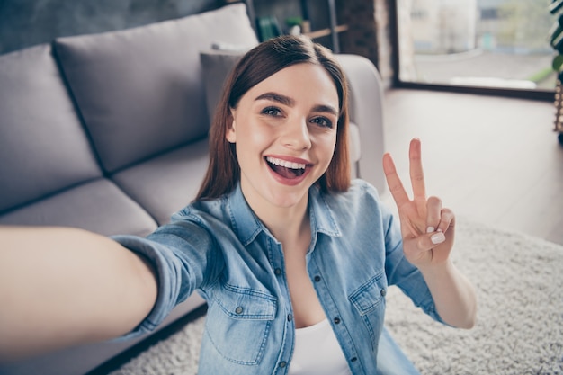 Gros plan d'une étudiante gaie positive faire un selfie show vsign