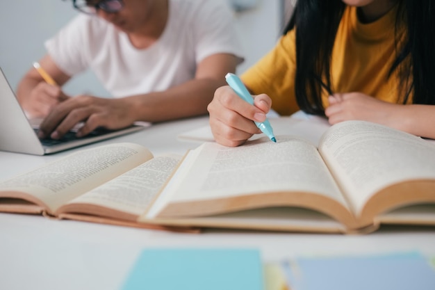 Gros plan sur des étudiants asiatiques qui lisent des livres et étudient le tutorat ensemble