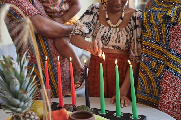 Gros plan d'une famille africaine de quatre personnes en costumes nationaux brûlant les sept bougies pour les vacances de kwanzaa