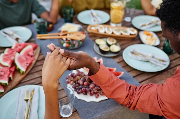 Gros plan sur une famille afro-américaine disant grâce à table à l'extérieur et se tenant la main pendant le rassemblement