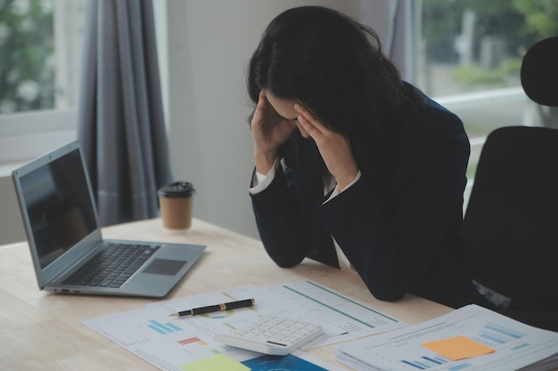 Gros plan femme d'affaires à l'aide d'une calculatrice et d'un ordinateur portable pour faire des finances mathématiques sur un bureau en bois statistiques de comptabilité fiscale et concept de recherche analytique