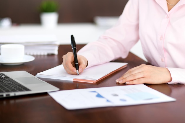 Gros plan d'une femme d'affaires écrivant dans un cahier.