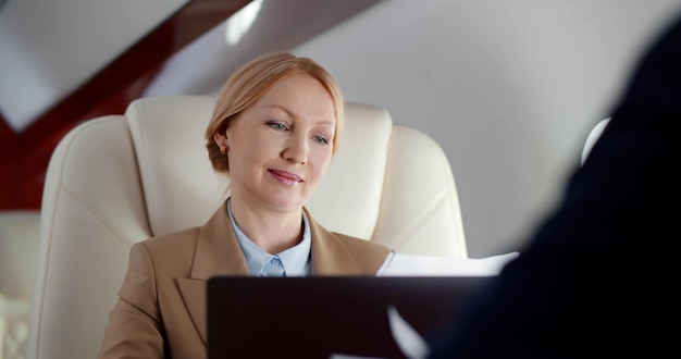 Gros plan sur une femme d'affaires mature lisant un contrat et discutant avec un partenaire volant en première classe