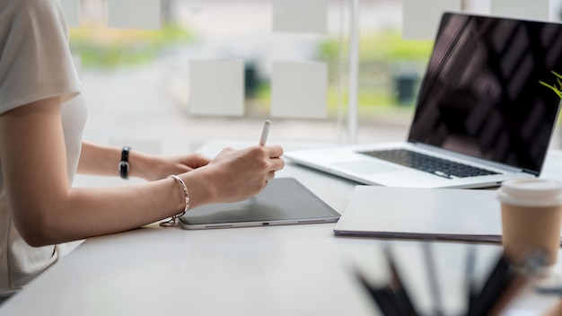 Gros plan d'une femme d'affaires travaillant sur une tablette au bureau.