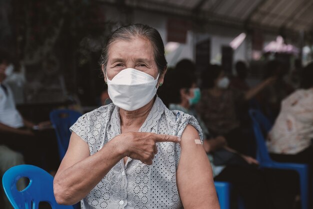 Gros plan d'une femme âgée est allée vacciner le coronavirus covid19 pointant l'épaule avec un bandage