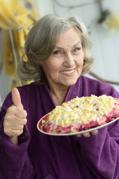 Gros plan d'une femme âgée avec salade et pouce vers le haut