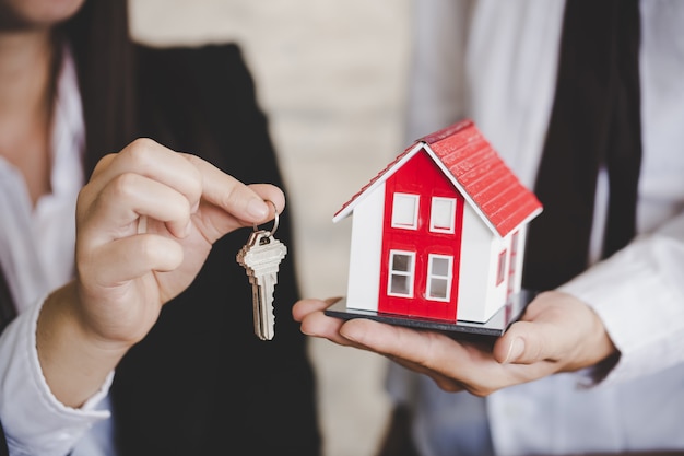 Gros plan de femme agent immobilier donnant la clé du nouvel appartement au client.