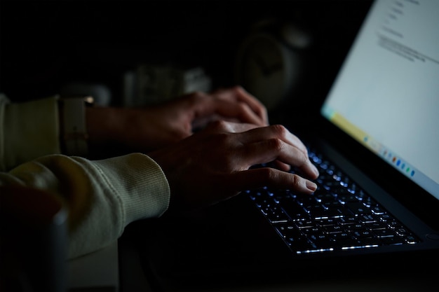 Gros plan d'une femme anonyme tapant sur un clavier d'ordinateur portable la nuit communication en ligne et travail