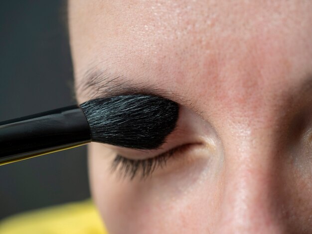 Gros plan d'une femme appliquant une ombre au pinceau sur les paupières. Maquillage à la maison, beauté