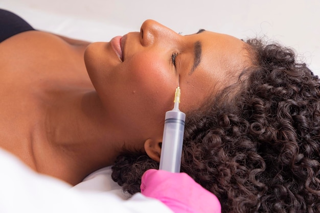 Gros plan d'une femme appliquant de l'ozone sur son visage pour un traitement cosmétique