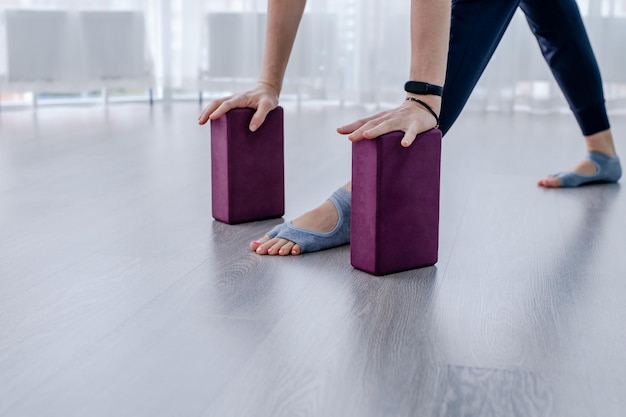 Gros plan une femme appuie ses paumes sur des blocs de yoga violets