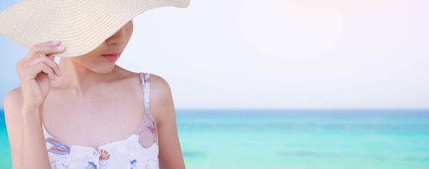 Gros plan femme attraper un chapeau sur l'image floue de la mer bleue