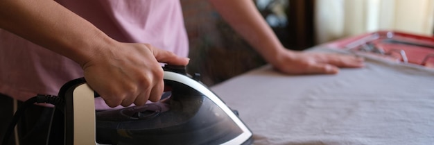 Gros plan d'une femme au foyer fers à repasser le linge de lit sur une planche à repasser femme faisant le ménage ménage