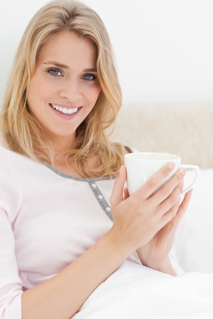 Gros plan, Femme au lit, avec une tasse dans les mains comme elle attend avec impatience