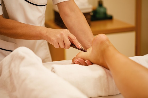 Gros plan d'une femme ayant un massage traditionnel des pieds de réflexologie au spa