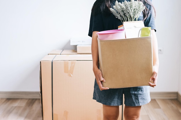 Un gros plan d'une femme avec des boîtes de carton qui emménage dans une nouvelle maison.