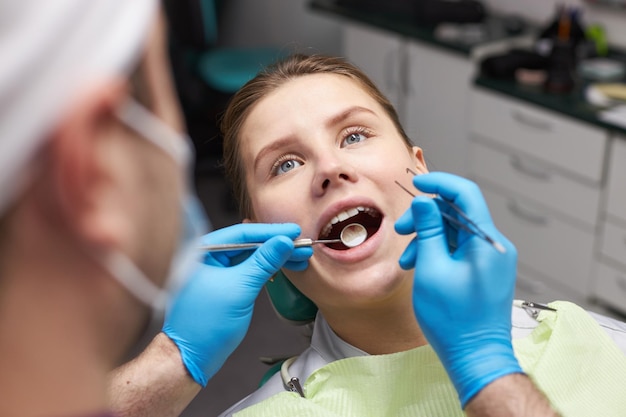 Gros plan sur une femme avec la bouche ouverte lors d'un examen dentaire Dentiste examinant les dents et les gencives d'une patiente