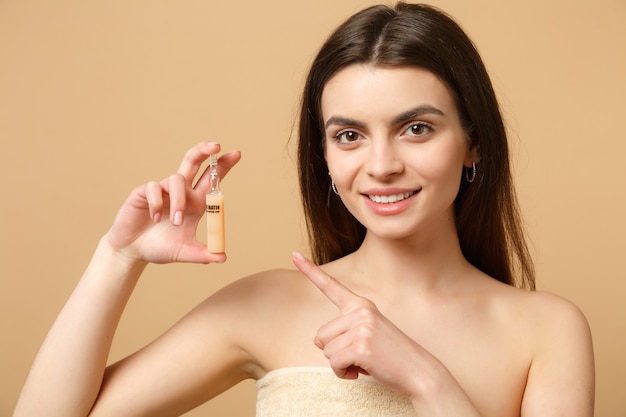 Gros plan sur une femme brune à moitié nue des années 20 avec une peau parfaite, maquillage nu isolé sur un mur pastel beige, portrait. Concept de procédures cosmétiques de soins de la peau.