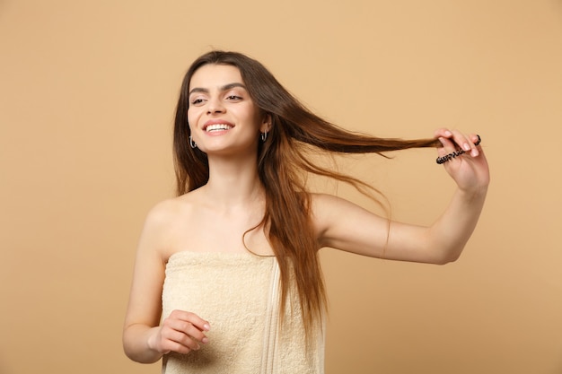 Gros plan sur une femme brune à moitié nue des années 20 avec une peau parfaite, maquillage nu isolé sur un mur pastel beige, portrait. Concept de procédures cosmétiques de soins de la peau.