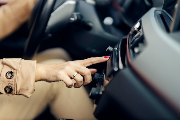 Gros plan d'une femme changeant de station de radio dans sa voiture