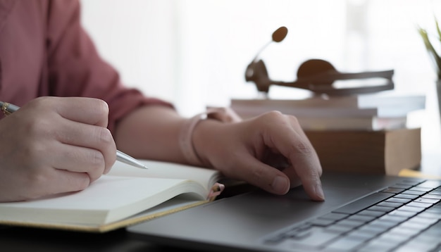 Gros plan d'une femme ou d'un comptable tenant un crayon travaillant sur une calculatrice pour calculer un rapport de données financières, un document de comptabilité et un ordinateur portable au bureau, concept d'entreprise