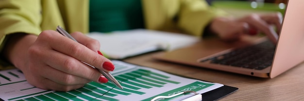 Gros plan d'une femme comptable travaillant avec des données statistiques et tapant sur des documents d'ordinateur portable modernes