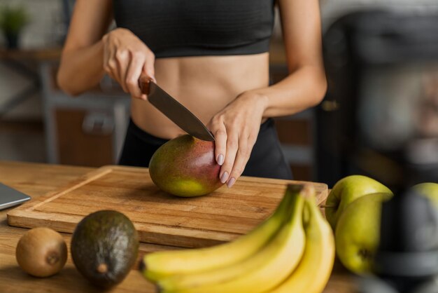 Gros plan d'une femme coupant la mangue face à la caméra pour son concept d'alimentation saine