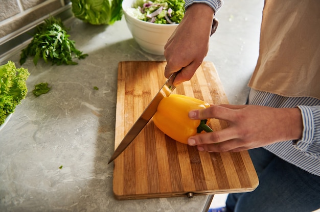 Gros plan d'une femme coupant le poivre pour préparer la salade. Fermer