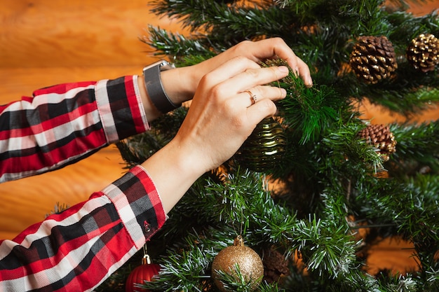 Gros Plan D'une Femme Dans Une Chemise à Carreaux Accroche Une Belle Boule Brillante Sur Un Arbre De Noël