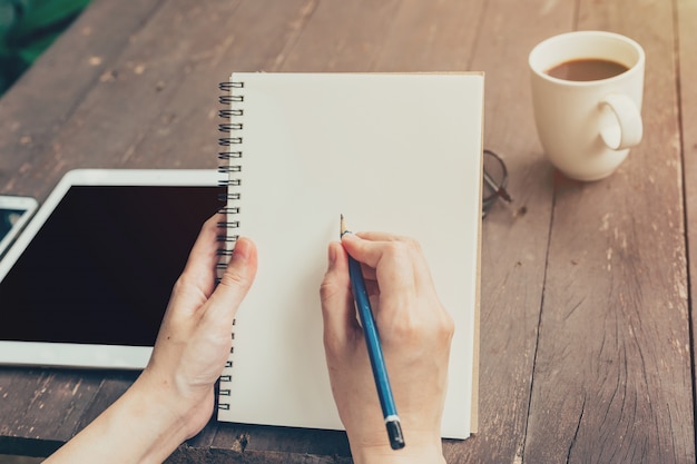 Gros plan, femme, écriture, cahier, sur, bois, table.