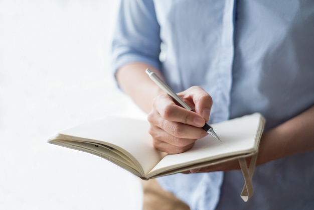 Gros plan de femme écrivant dans le cahier