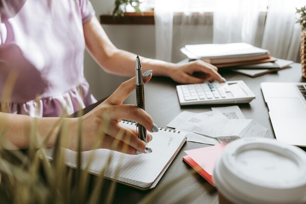 Gros plan d'une femme écrivant quelque chose sur le papier au bureau