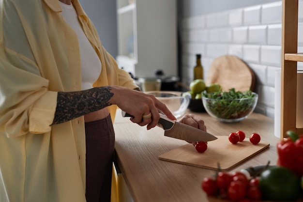 Gros plan d'une femme enceinte cuisinant des repas sains en coupant des légumes dans la cuisine