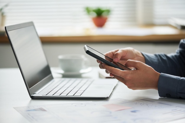 Gros plan d'une femme entrepreneur avec un téléphone portable regardant des données en ligne