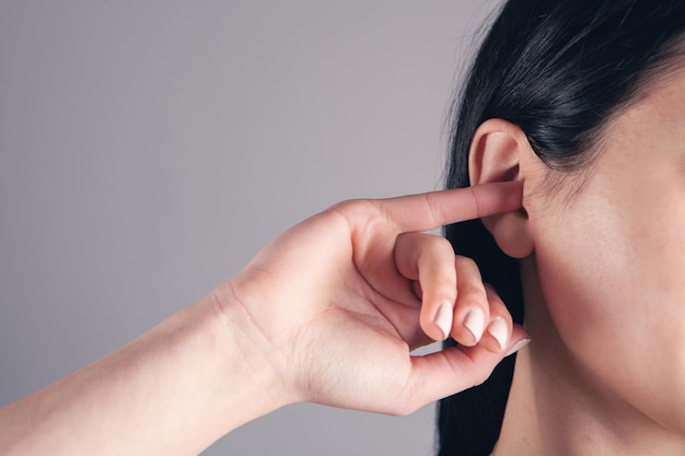 Gros plan femme essayant de nettoyer son oreille avec son doigt