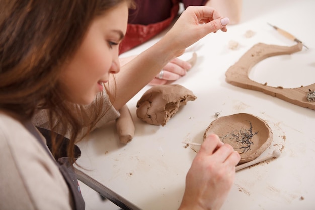 Gros plan d'une femme faisant une assiette en céramique à l'atelier d'argile