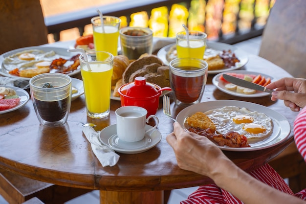 Gros plan d'une femme avec une fourchette et un couteau mangeant des œufs au plat et du bacon photo stock