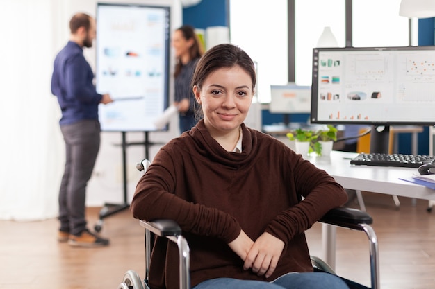 Photo gros plan d'une femme handicapée invalide paralysée collègue de travail regardant l'avant souriant travaillant dans un bureau d'affaires économique