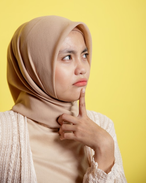 Gros plan femme hijab avec une expression heureuse de penser quelque chose d'isolé sur fond jaune