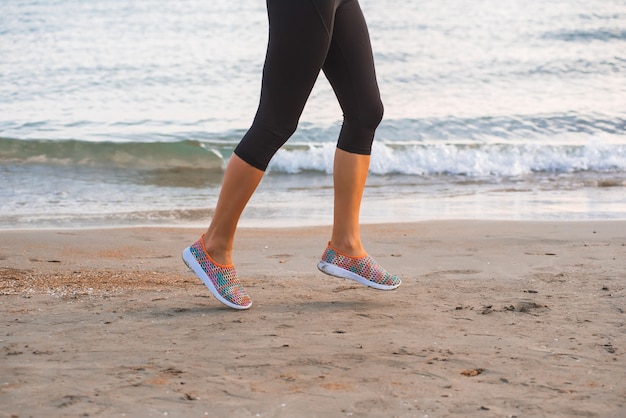 Gros plan, femme, jambes, courant, plage, lever soleil, matin