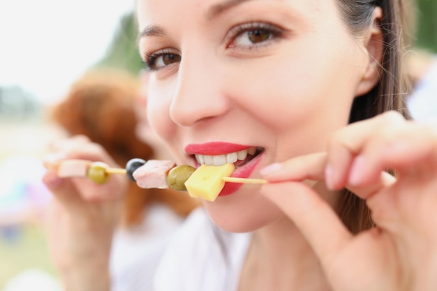 Gros plan d'une femme joyeuse tenant un bâton avec du fromage d'olive et du bacon heureuse belle femme