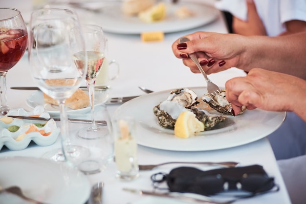 Gros plan de femme mangeant des huîtres fraîches au restaurant méditerranéen de fruits de mer.