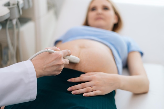 Gros plan sur une femme médecin effectuant une échographie du ventre d'une femme enceinte dans une clinique médicale. Concept de maternité heureuse et saine.