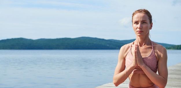 Gros plan d'une femme mûre dans un survêtement rose pratiquant le yoga près de la mer Concept de mode de vie sain